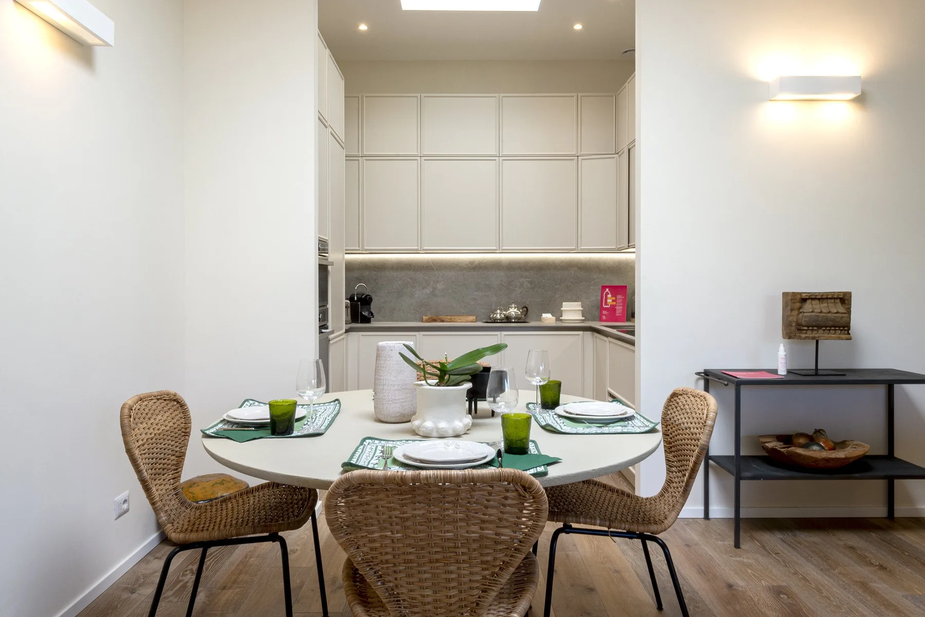 A dining area with a round table set with dishes and woven seating.