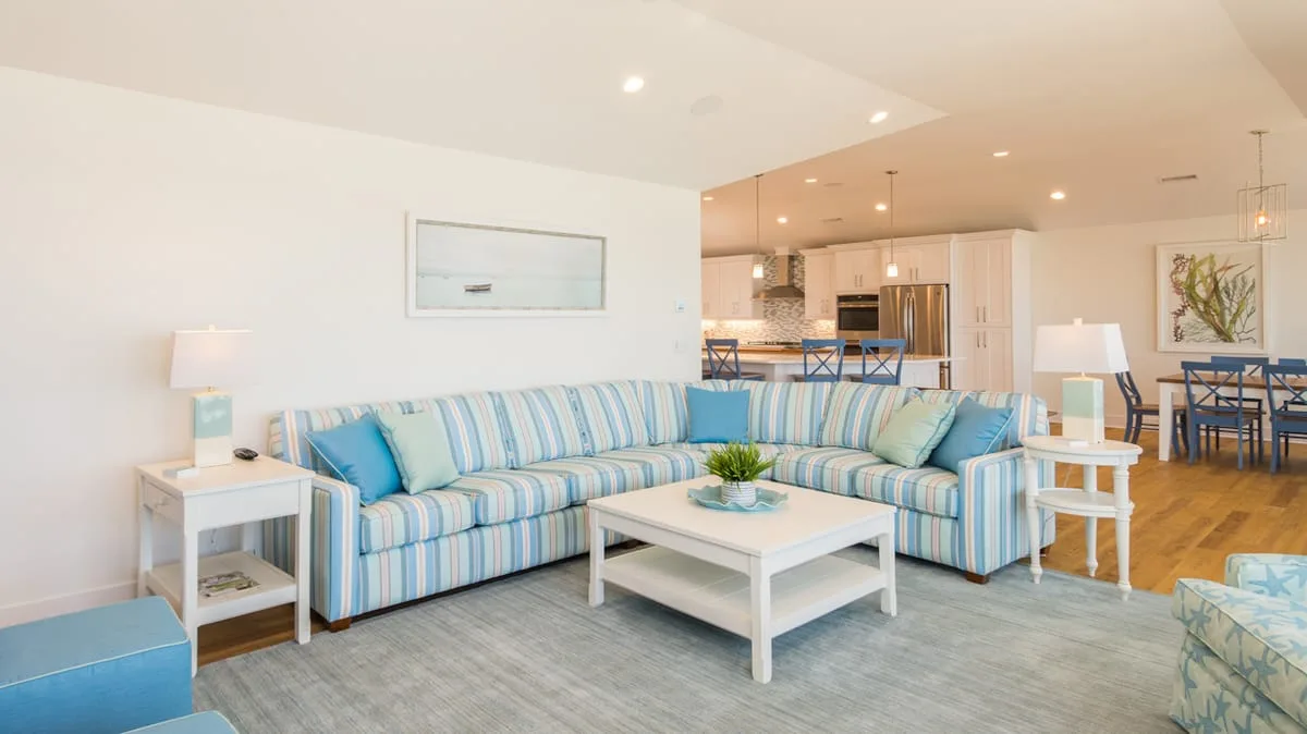 A bright living room with blue-striped seating and a white coffee table.