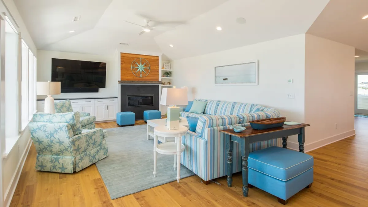 A bright living room with striped seating, a fireplace, and large windows.
