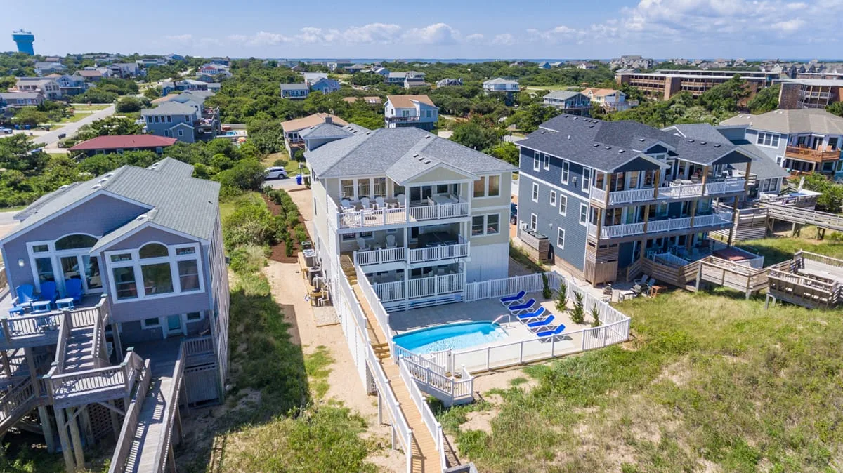 Aerial view of coastal houses, with a pool beside the central house.