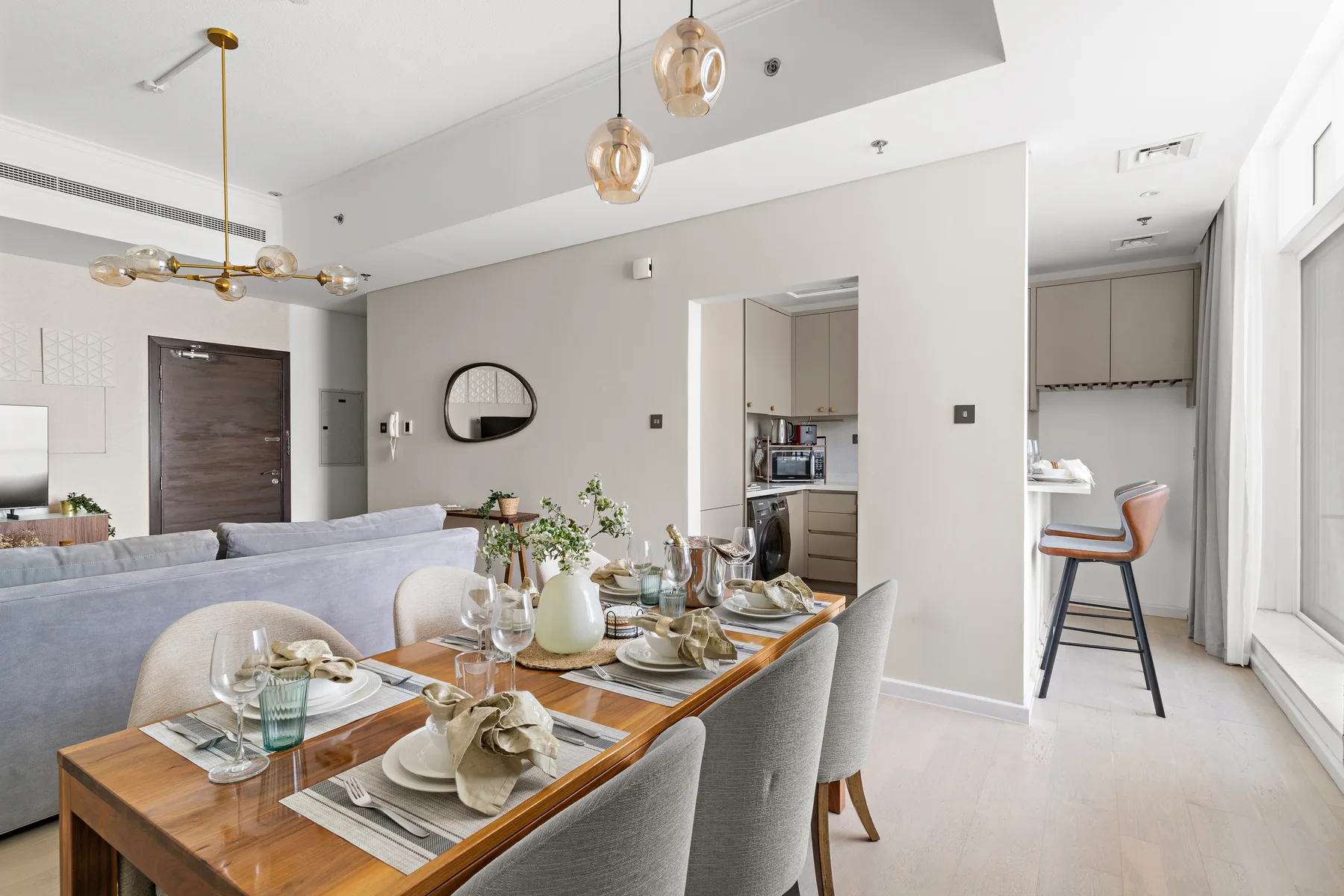 Comedor con la mesa puesta junto a una cocina luminosa.