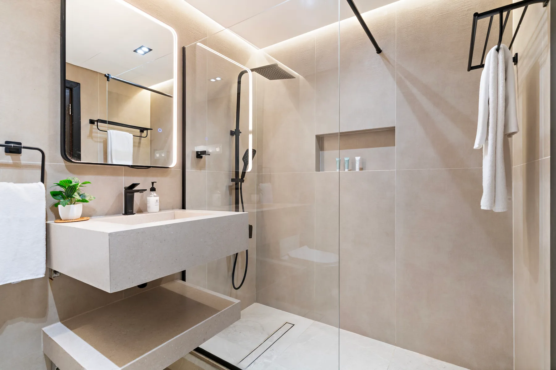Un baño moderno con lavabo suspendido, espejo y ducha.