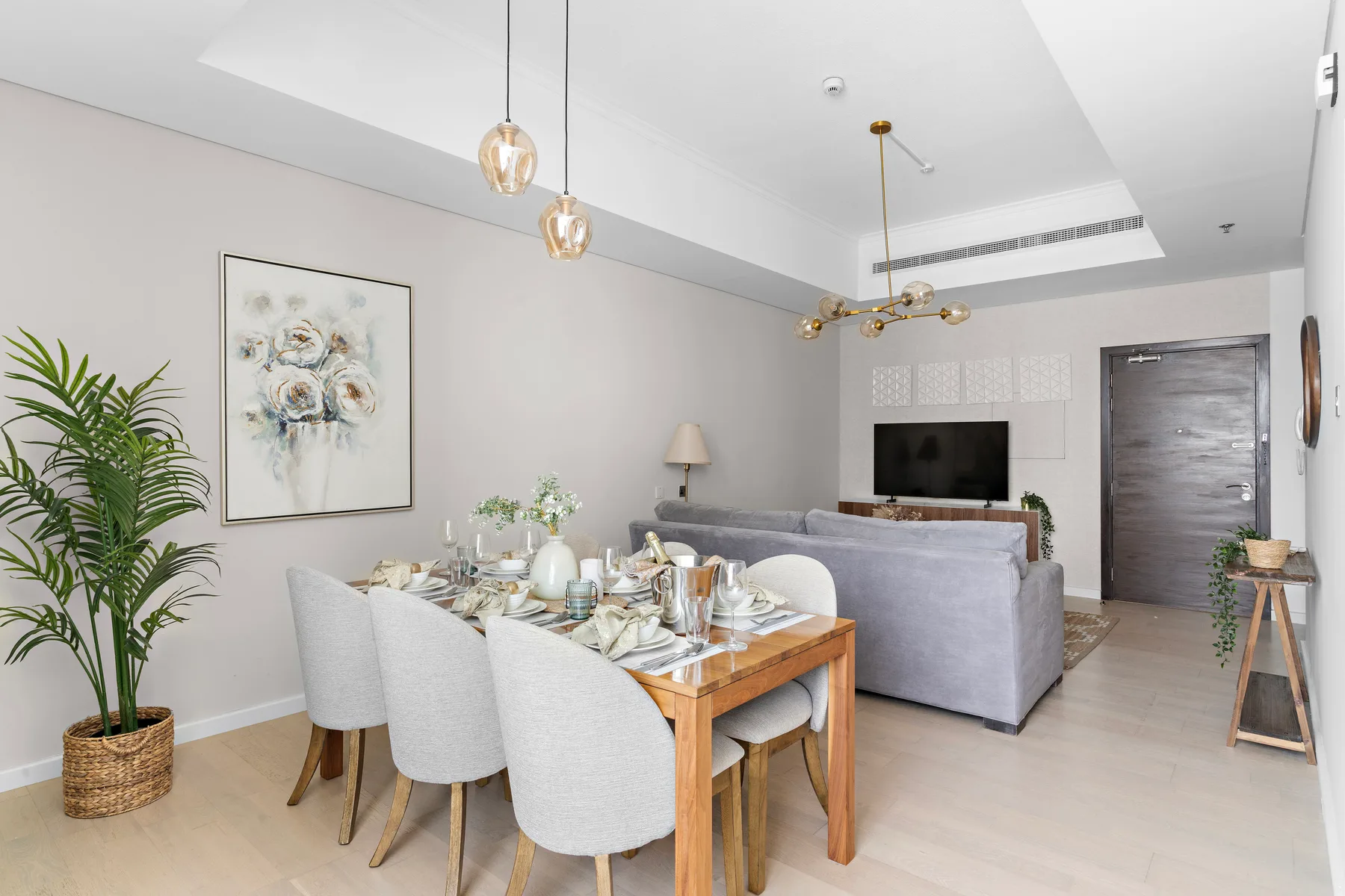 A dining area with a set table beside a living area with a television.