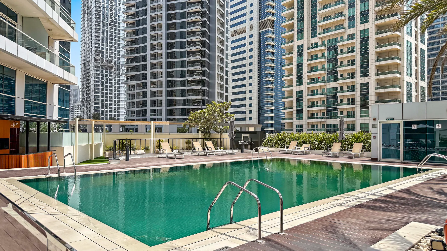 Una piscina está rodeada de edificios altos, con asientos de descanso junto al borde.