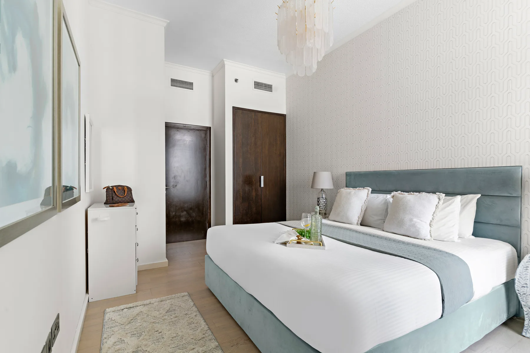 Un dormitorio luminoso con una cama bien tendida y una lámpara de noche.
