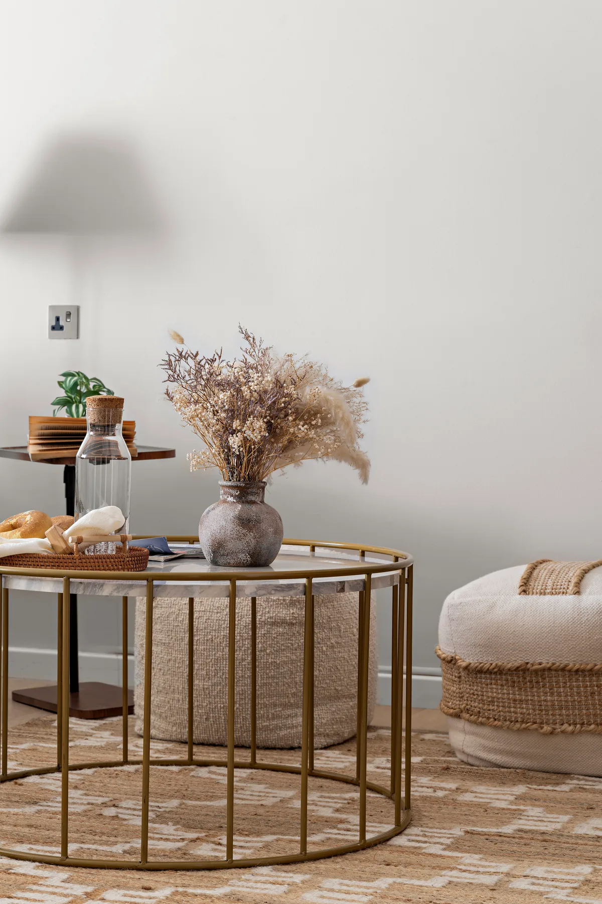 Una sala de estar con una mesa de centro redonda de vidrio y flores secas.