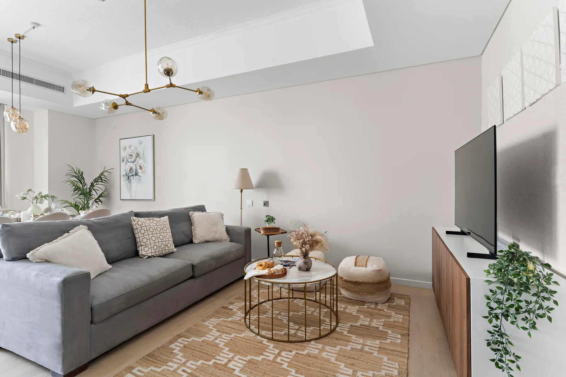 A living room with gray seating, a coffee table, and a television.