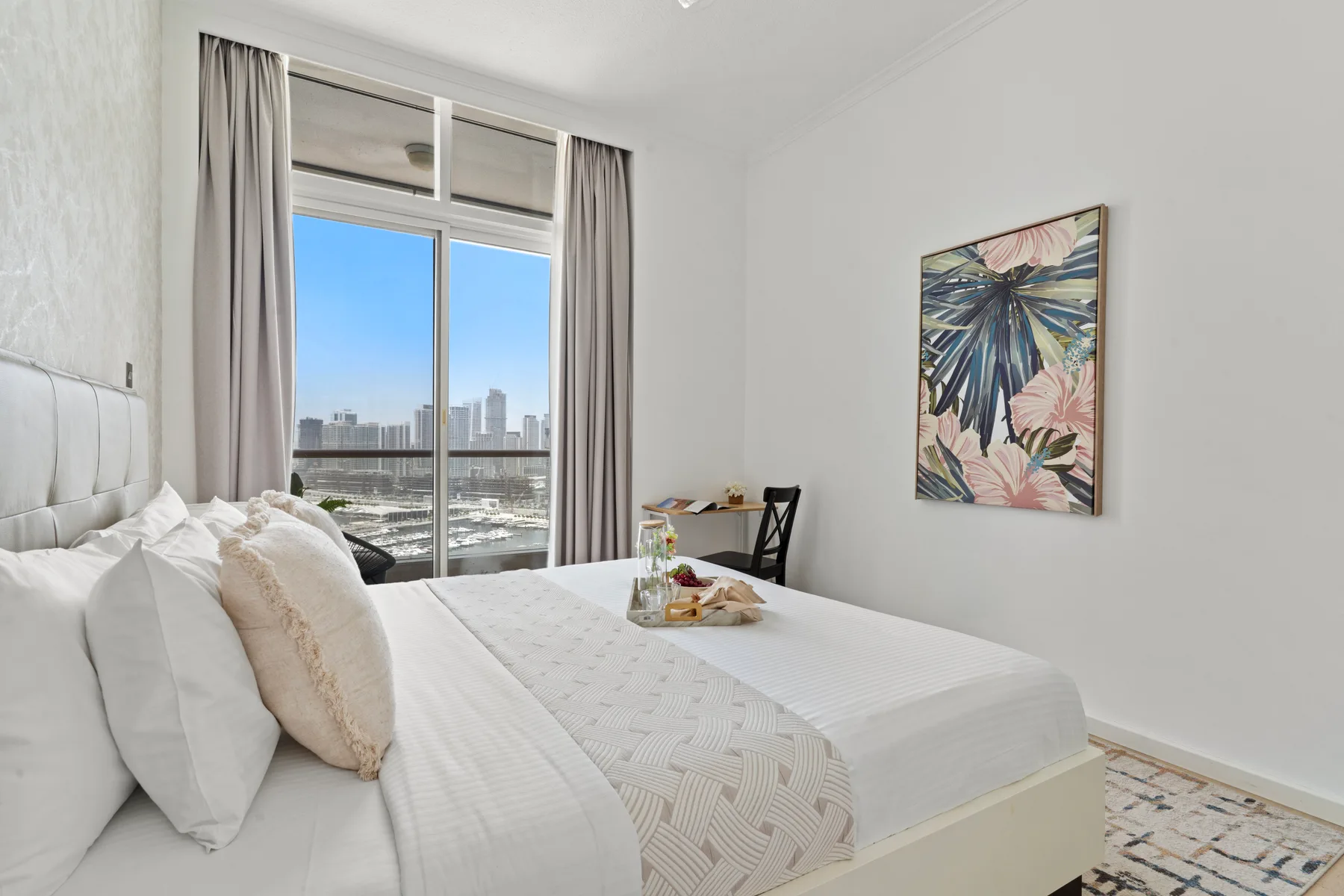 Un dormitorio luminoso con una cama bien hecha junto a una gran ventana.