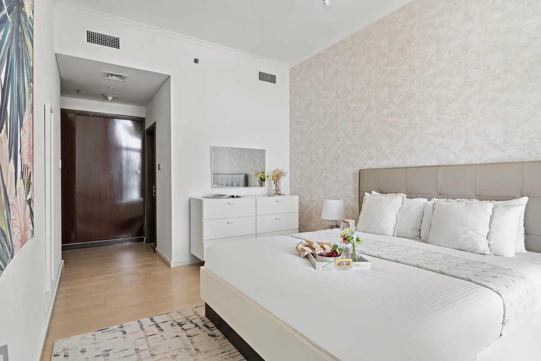 Un dormitorio luminoso con una cama grande y una cómoda blanca.