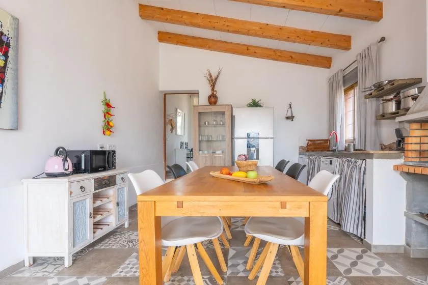 A dining area with a wooden table and chairs sits beside a compact kitchen.