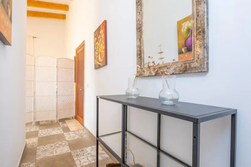 A bright hallway with a dark console table and decorative wall art.