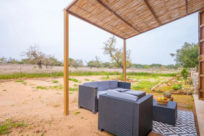 An outdoor seating area beneath a woven shade canopy overlooks a dry landscape.
