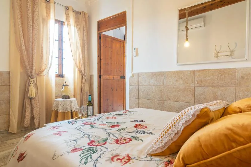 A bedroom with a floral bedspread, curtained window, and wooden door.