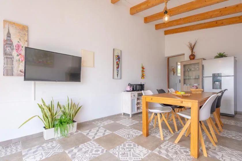 A dining area with a wooden table, chairs, and a television mounted on the wall.