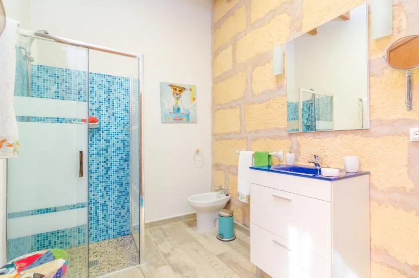 A bright bathroom with a glass shower and a sink vanity beneath a mirror.