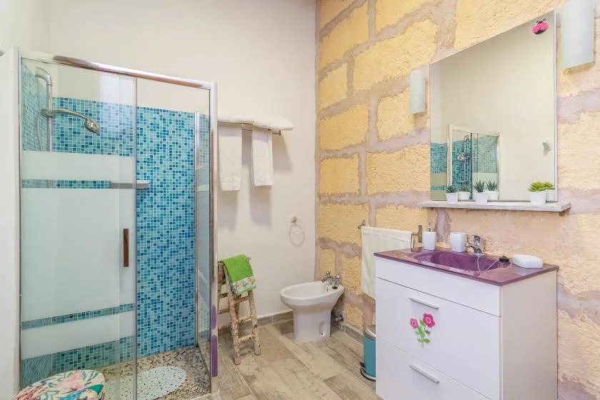 A bathroom with a tiled shower, sink vanity, and large wall mirror.