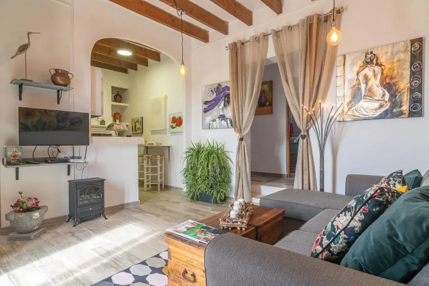A living room with seating, a television, and exposed ceiling beams.