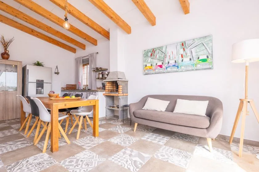A bright living and dining area with a table, seating, and exposed ceiling beams.