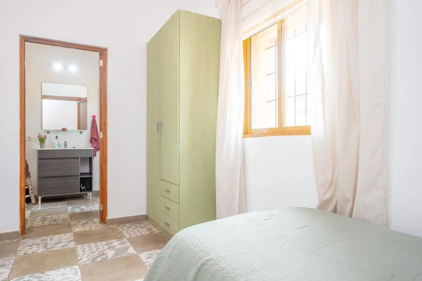 A bedroom with a bed, wardrobe, and bright window.