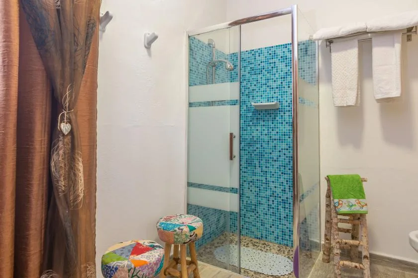 A bathroom with a glass shower and blue mosaic tile walls.