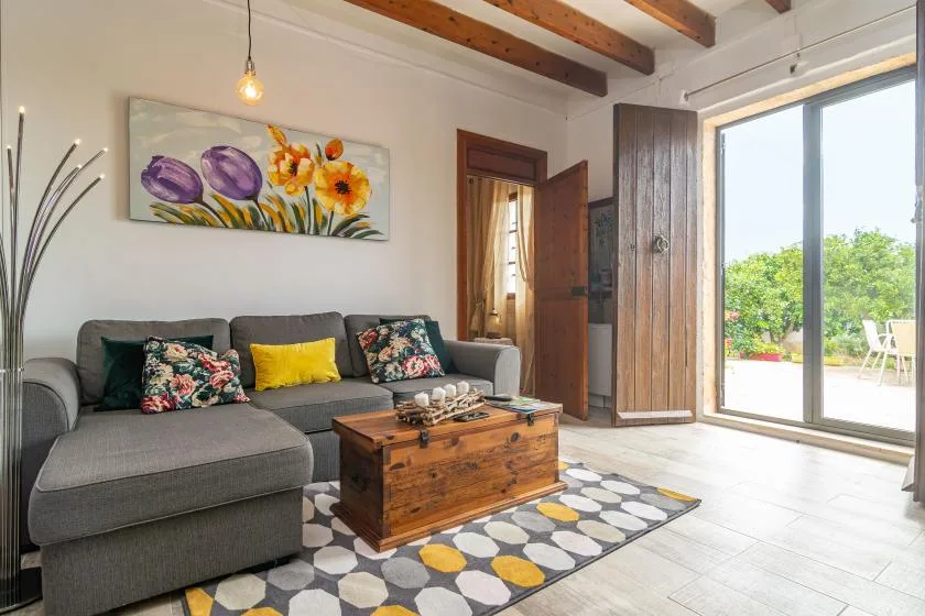 A living room with gray seating, a wooden coffee table, and an open patio door.
