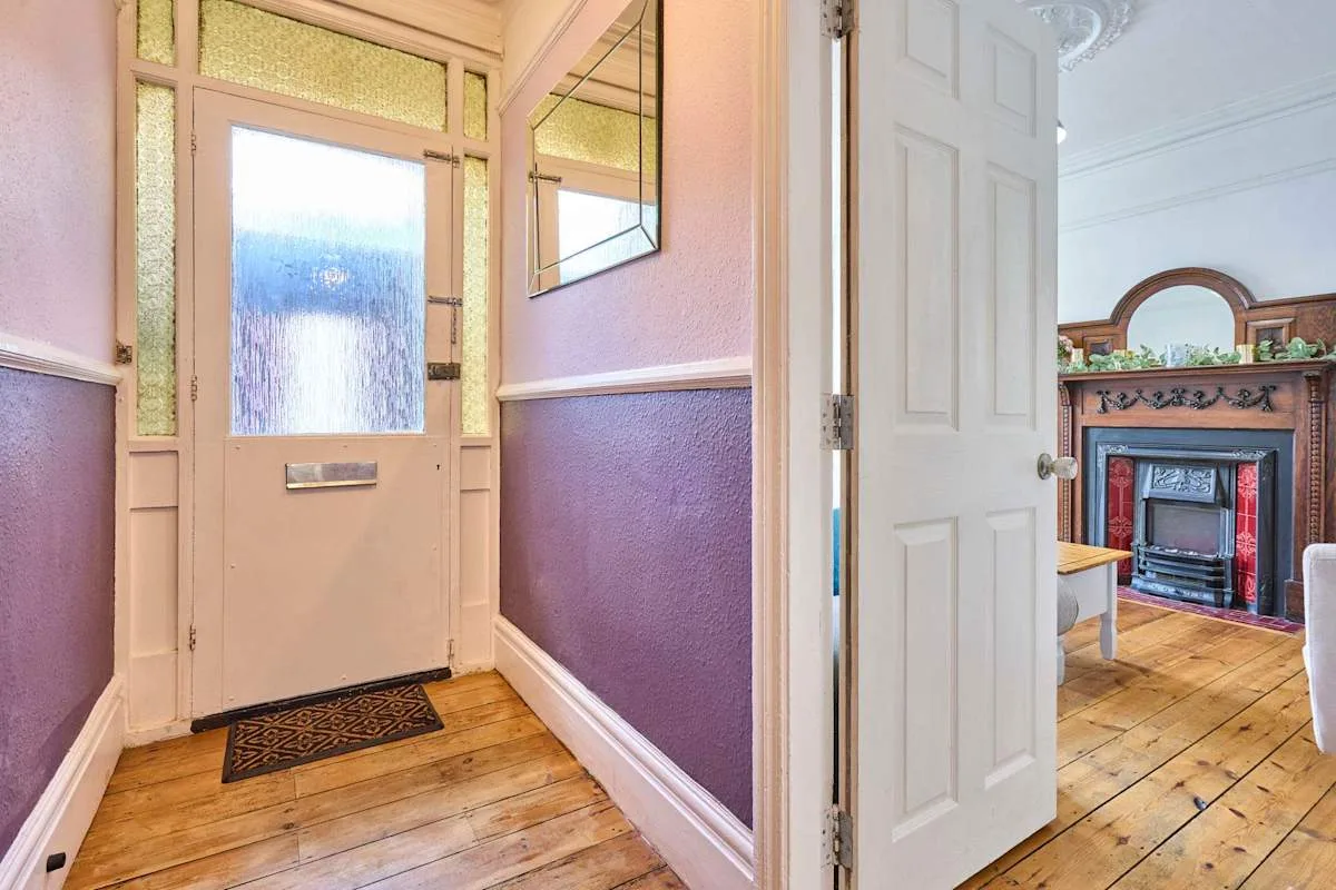 A colorful entryway opens into a room with a fireplace.