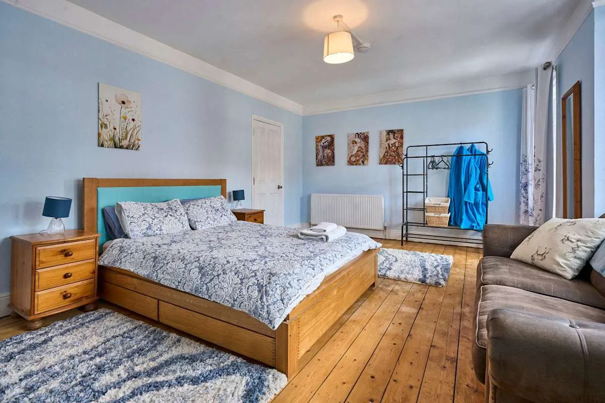 A bedroom with a wooden bed, bedside tables, and a sofa.