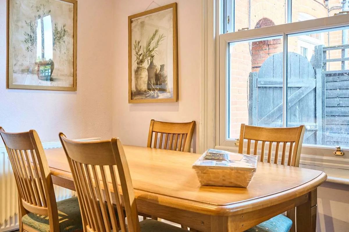 A dining area with a wooden table and chairs beside a large window.