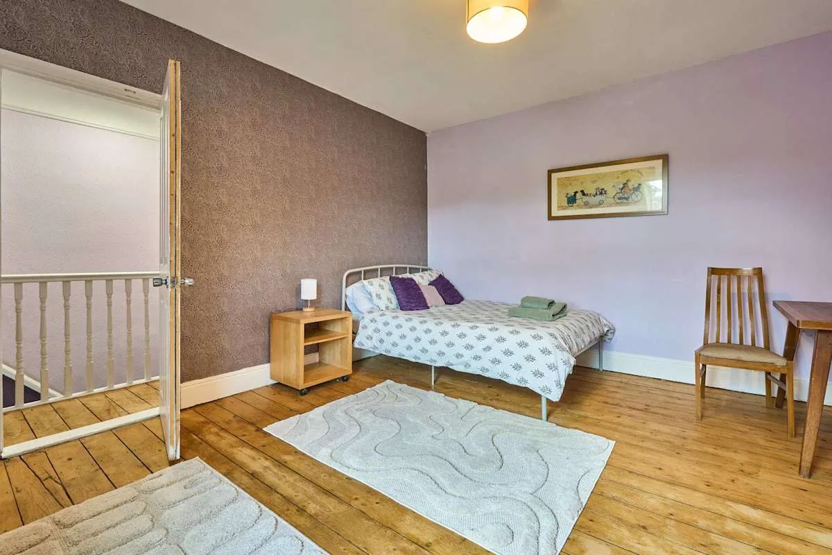 A bedroom with a bed, bedside table, and wooden floor.