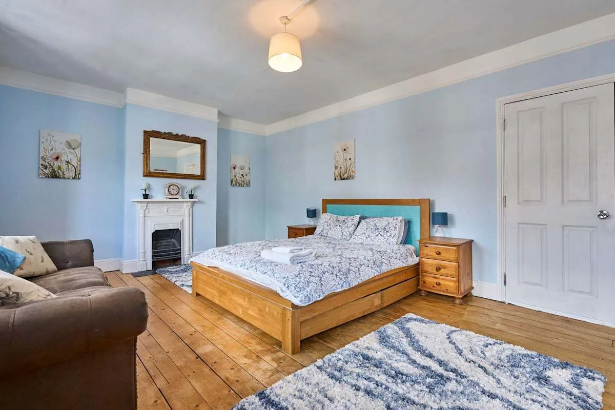 A bedroom with a wooden bed, a seating area, and a fireplace.