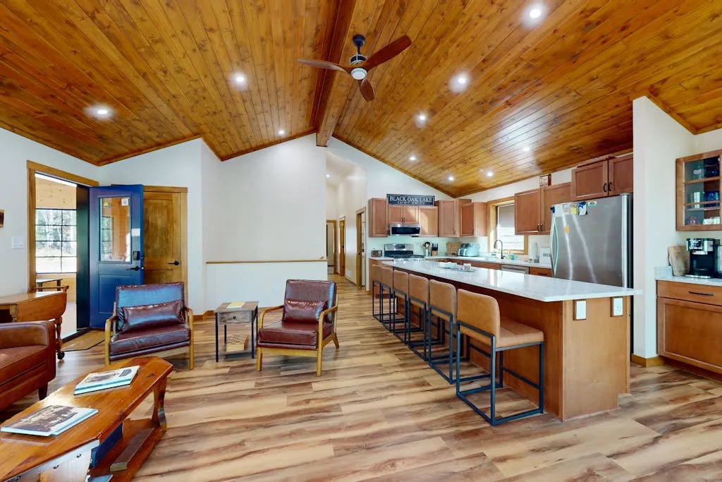Una sala de estar y cocina de planta abierta con una barra larga y asientos.