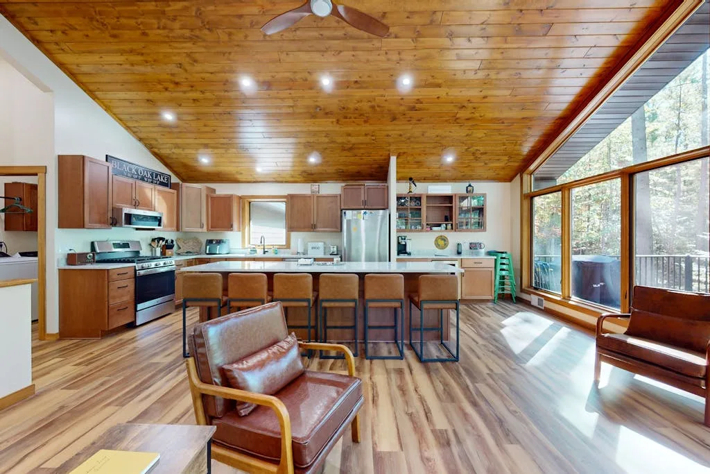 Una cocina y comedor abiertos con una isla larga y grandes ventanas.