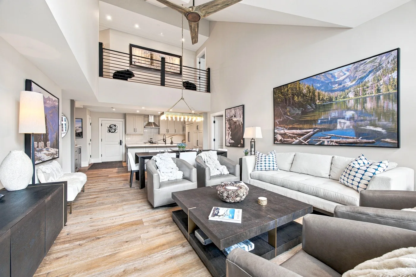 A spacious living room with gray seating, a coffee table, and an open kitchen.