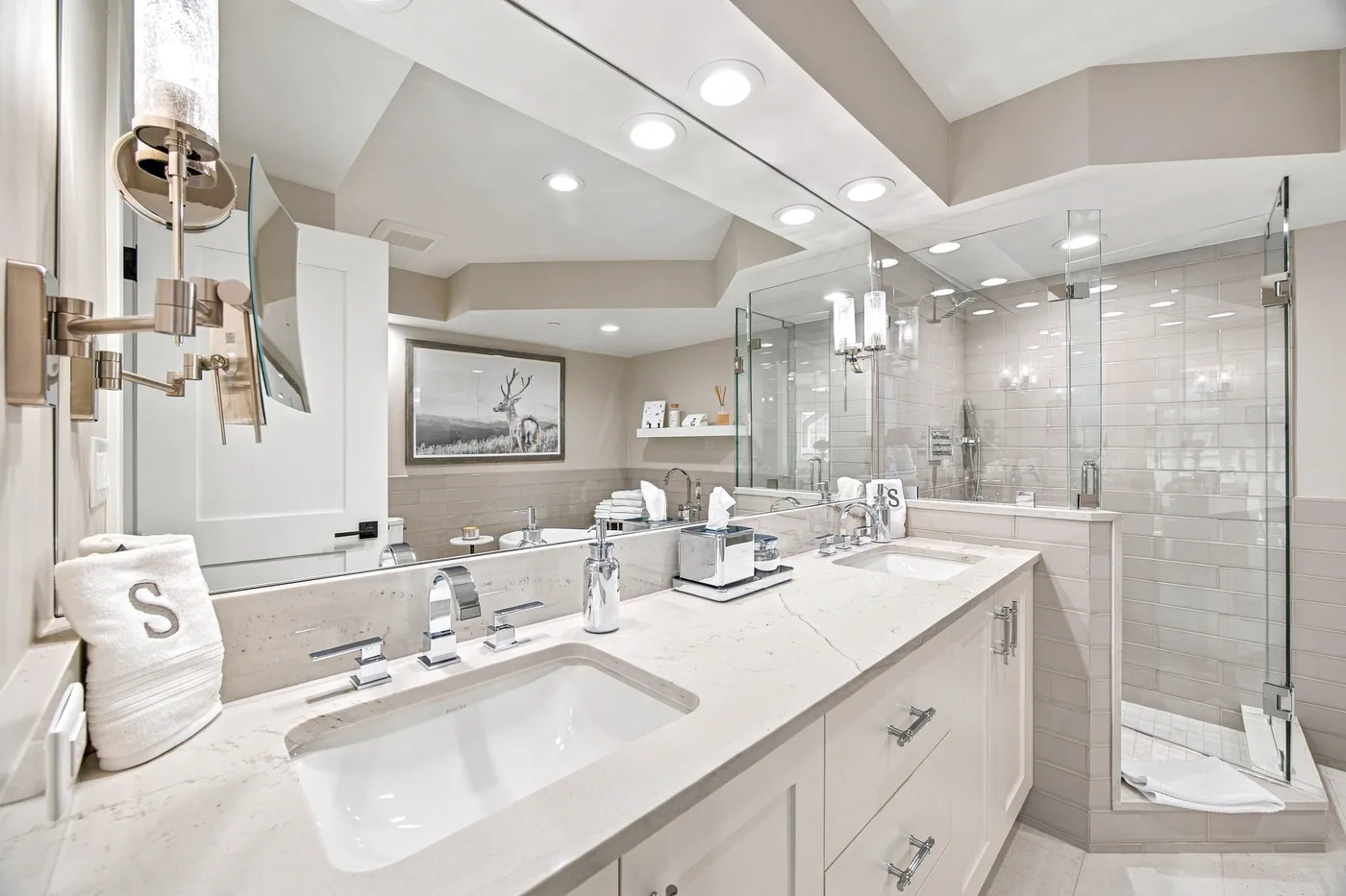 A bright bathroom with a long vanity and a glass shower.