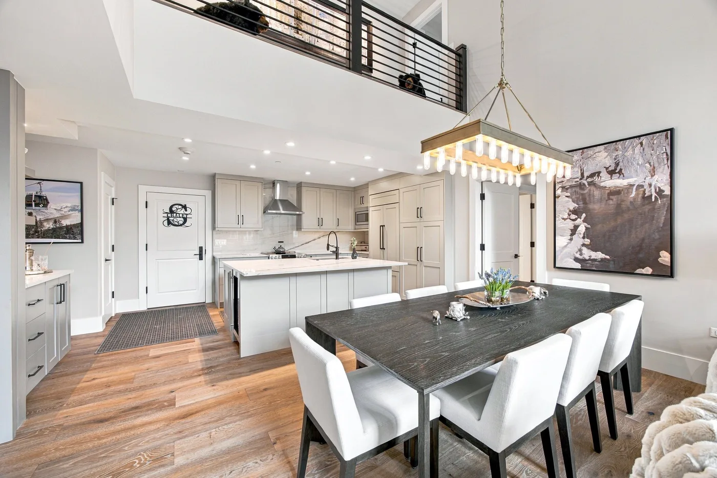 An open-plan kitchen and dining area with a large table beneath a hanging light.