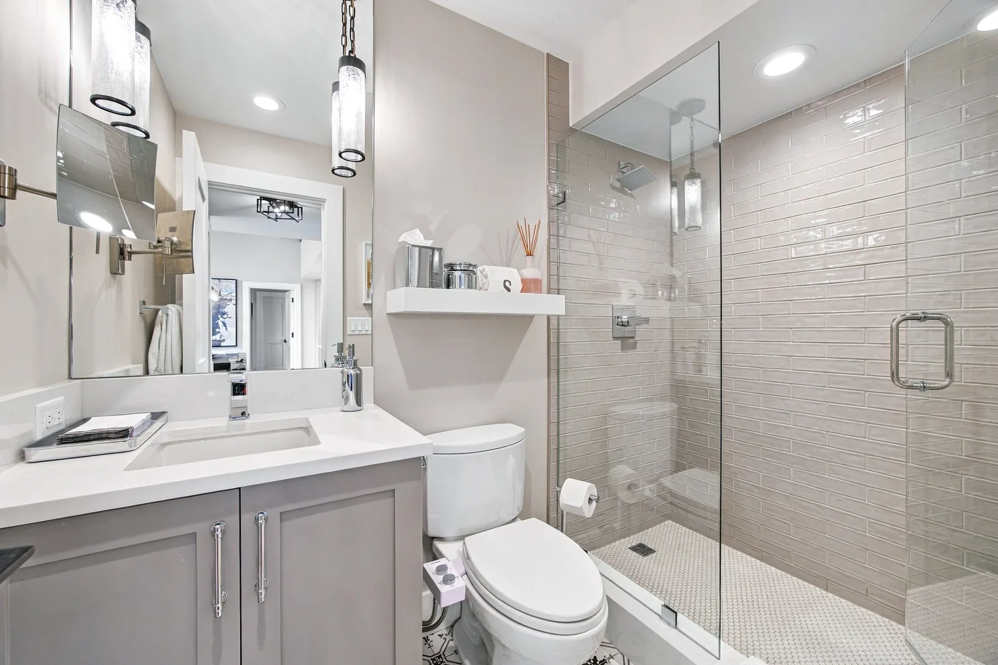 A bright bathroom with a vanity, toilet, and glass shower.