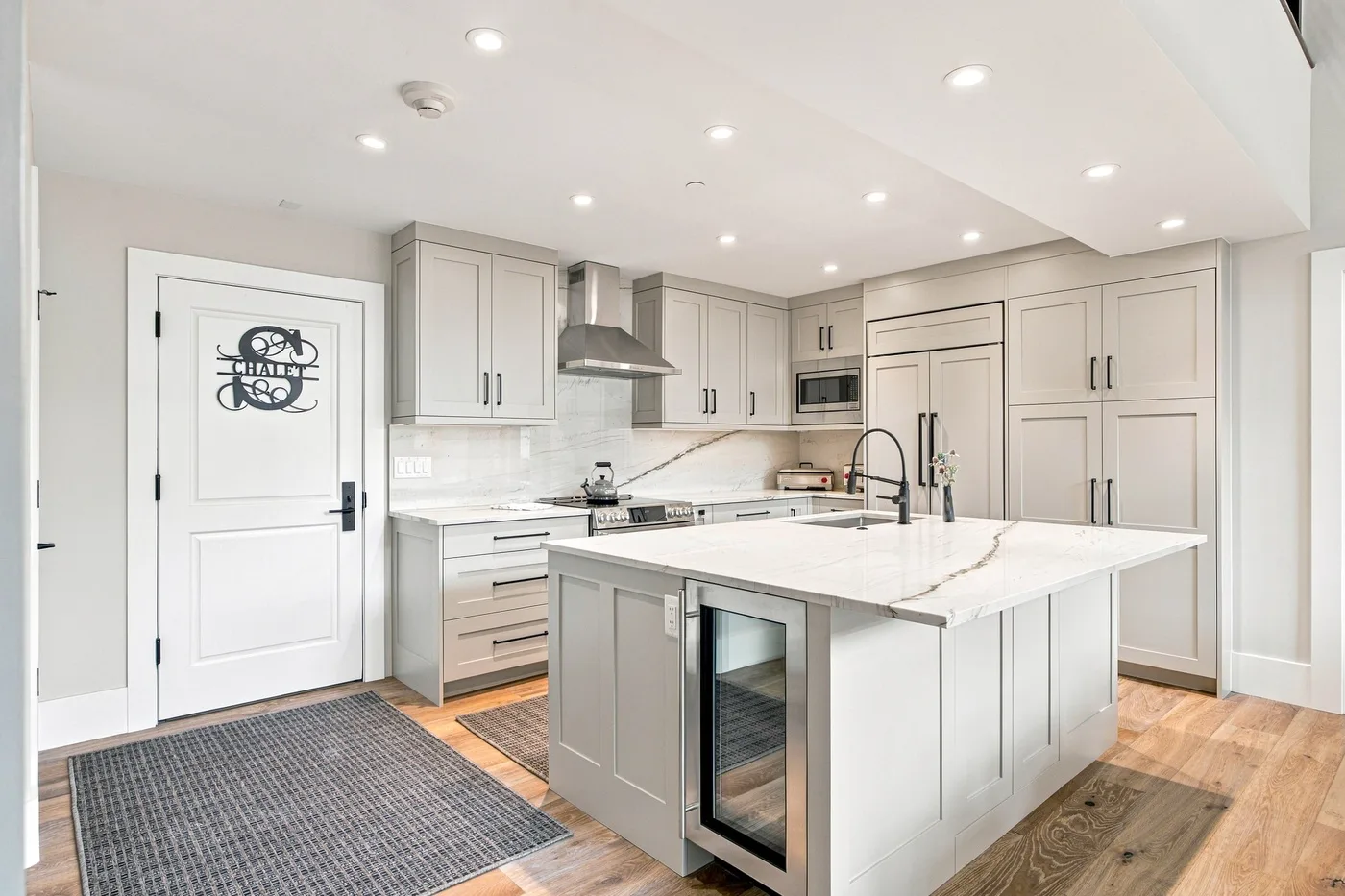 Bright kitchen with pale cabinetry, a large island, and wood flooring.