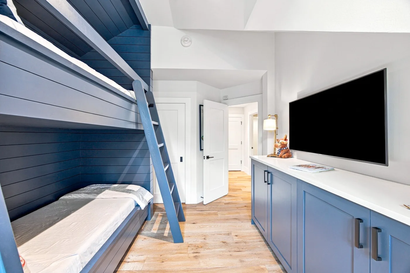 A blue bunk bed and built-in cabinets furnish a bright bedroom.