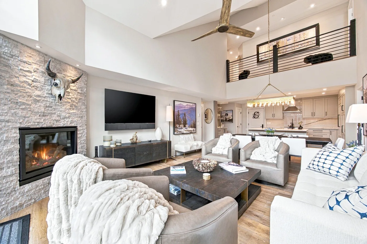 A bright open-plan living room with a fireplace and kitchen beyond.