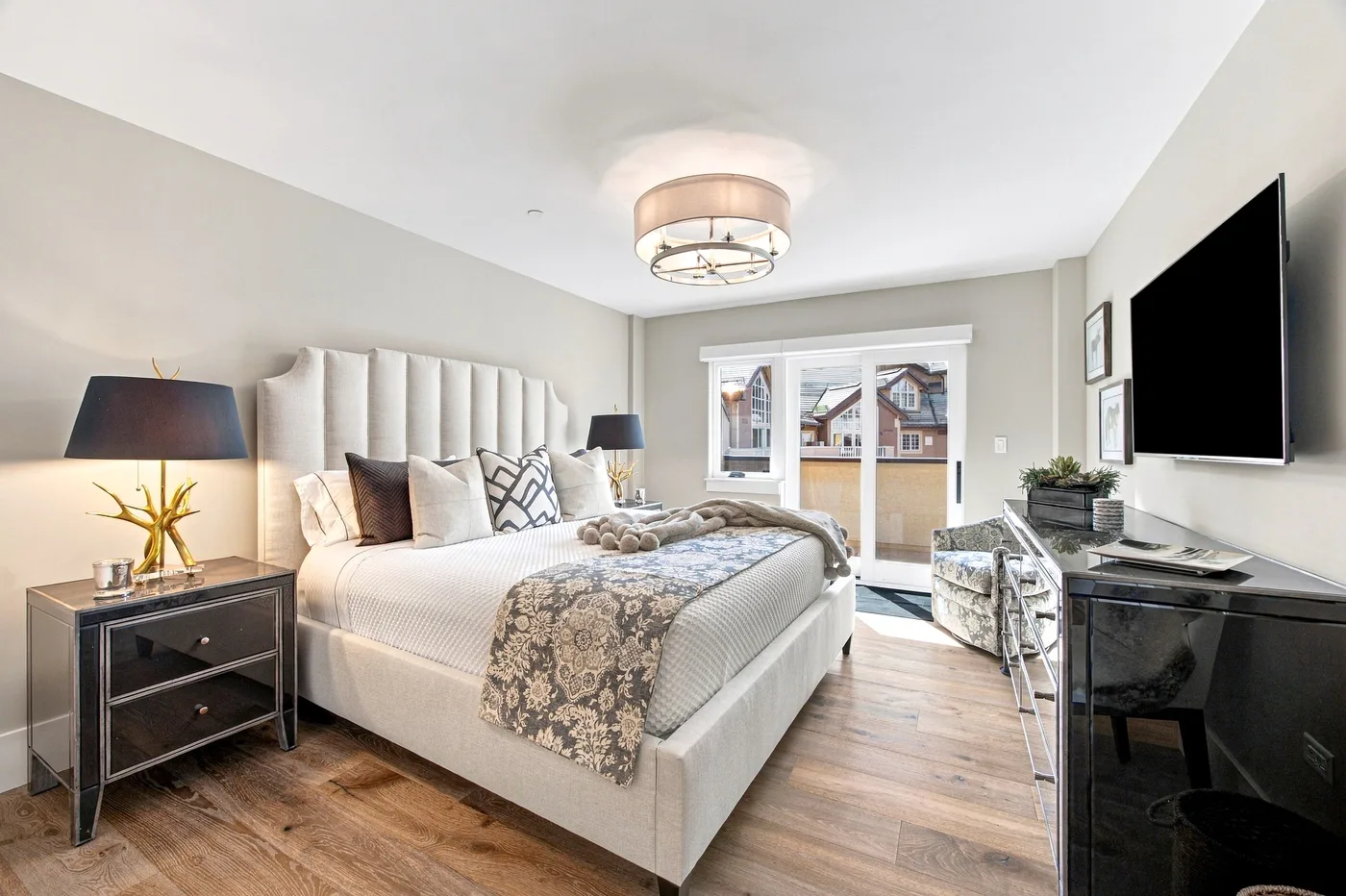 A bedroom with a large bed, bedside tables, and a wall-mounted television.