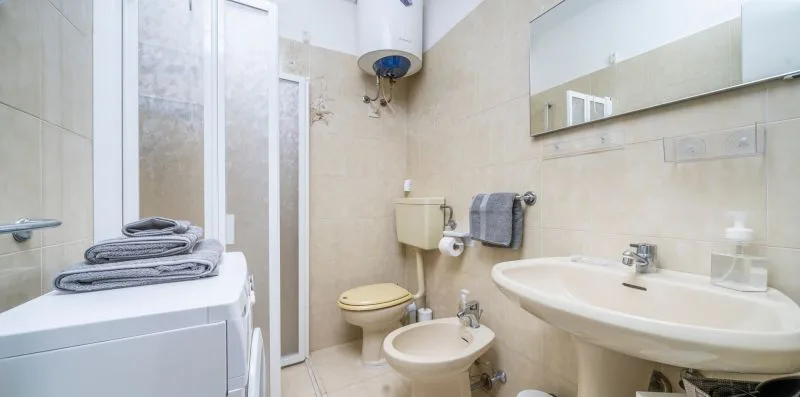 A bathroom with a sink, toilet, bidet, and washing machine.