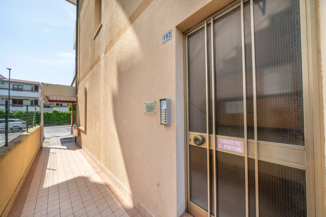 A tiled outdoor corridor runs alongside a building entrance.