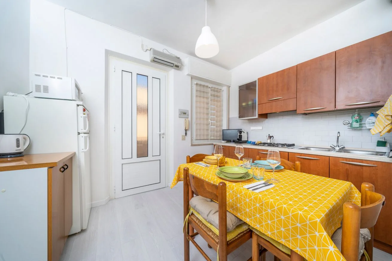 A bright kitchen and dining area with wooden cabinets and a yellow-covered table.