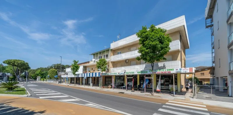 A street scene with a multi-story building, storefronts, and a pedestrian crossing.