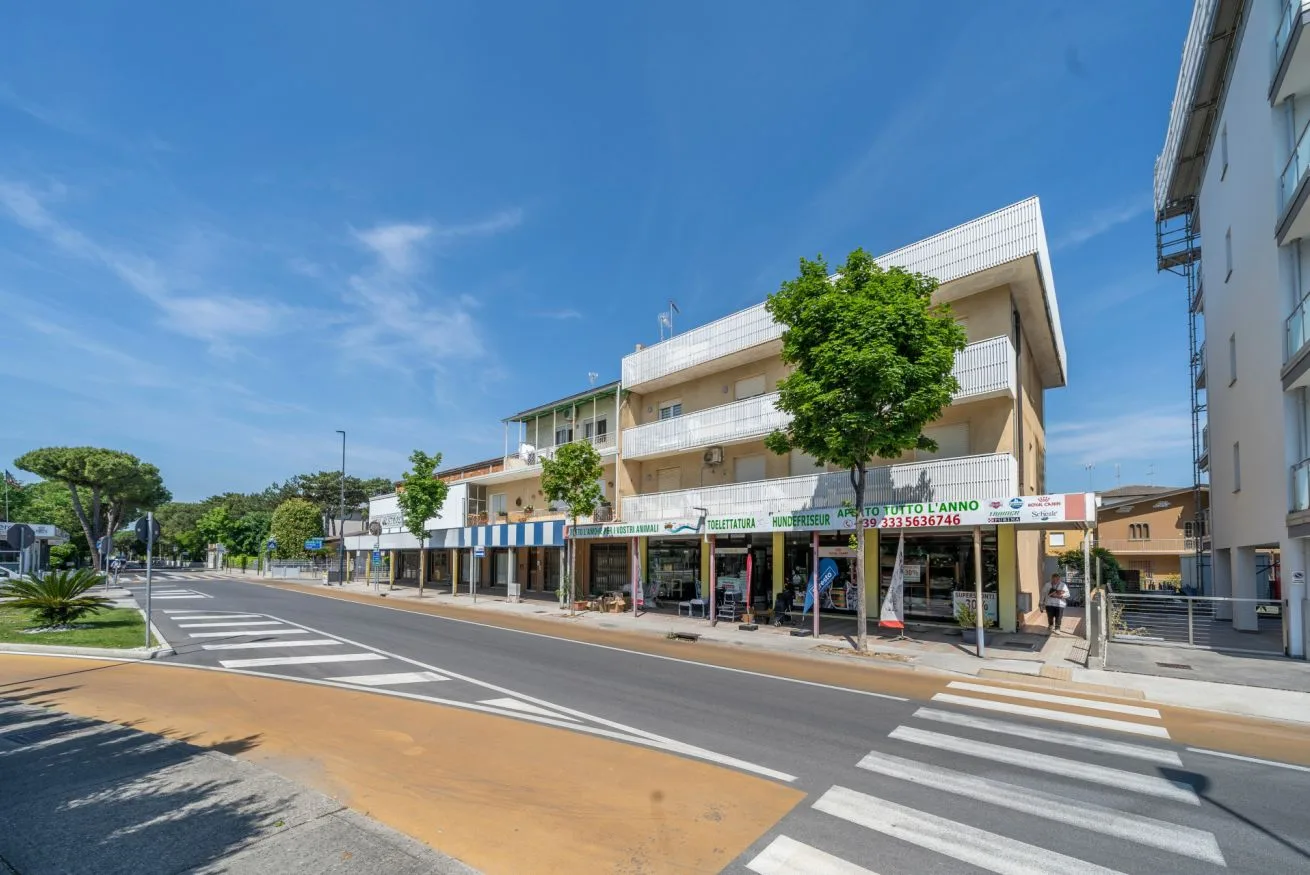 A street scene with storefronts beneath a multi-story building and a marked crosswalk.