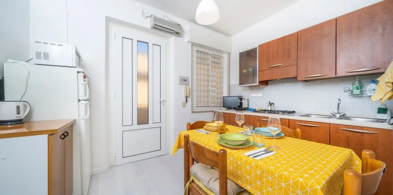 A bright kitchen and dining area with wooden cabinets and a table set with dishes.