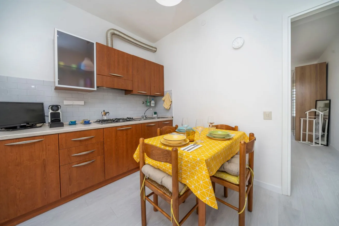 A kitchen with wooden cabinets and a dining table covered with a yellow tablecloth.