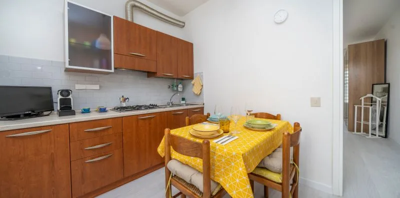 A kitchen and dining area with wooden cabinets and a table covered in a yellow cloth.