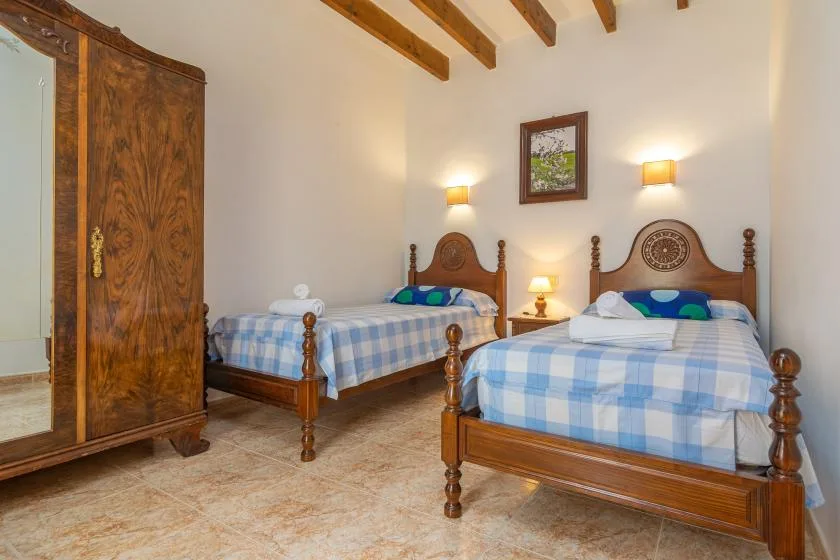 Un dormitorio con dos camas de madera vestidas con ropa de cuadros azules.
