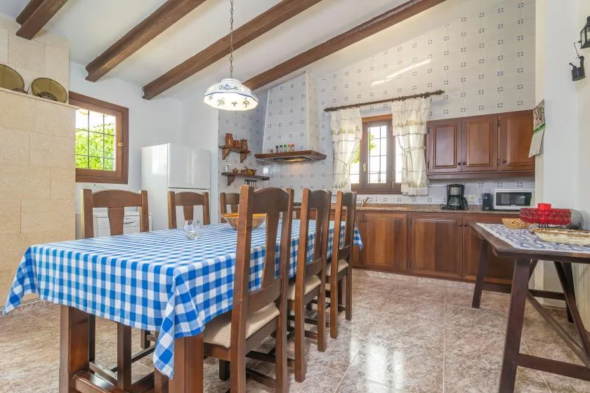 Un comedor con un mantel a cuadros junto a una cocina con gabinetes de madera.